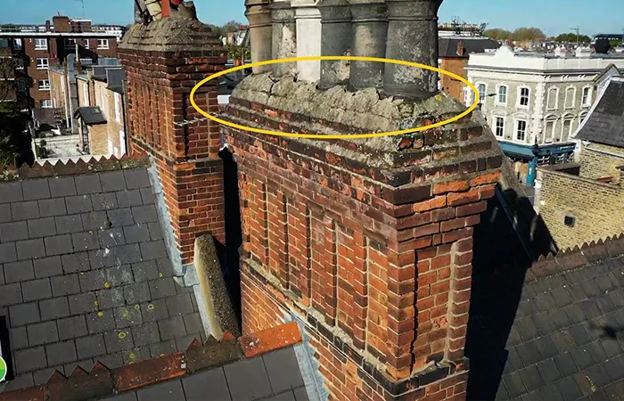 Chimney stack with visible deterioration and moss growth, indicating potential drainage issues and maintenance needs.